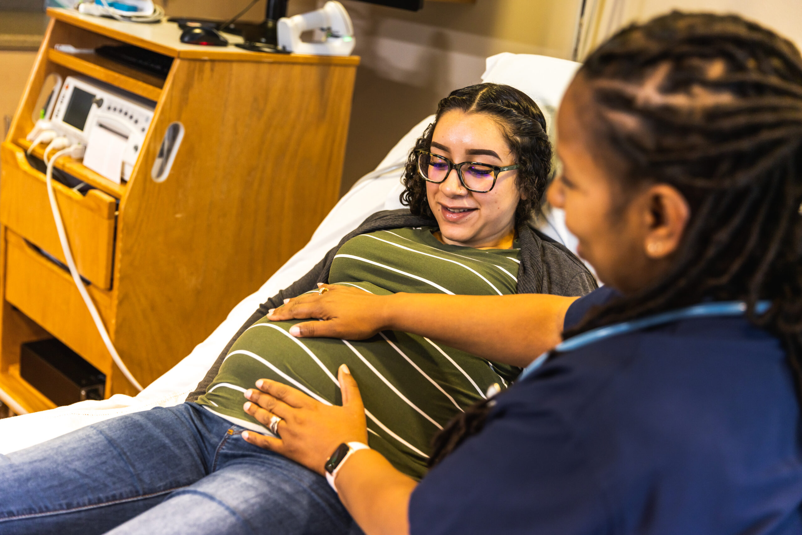 Woman checking pregnant woman's belly