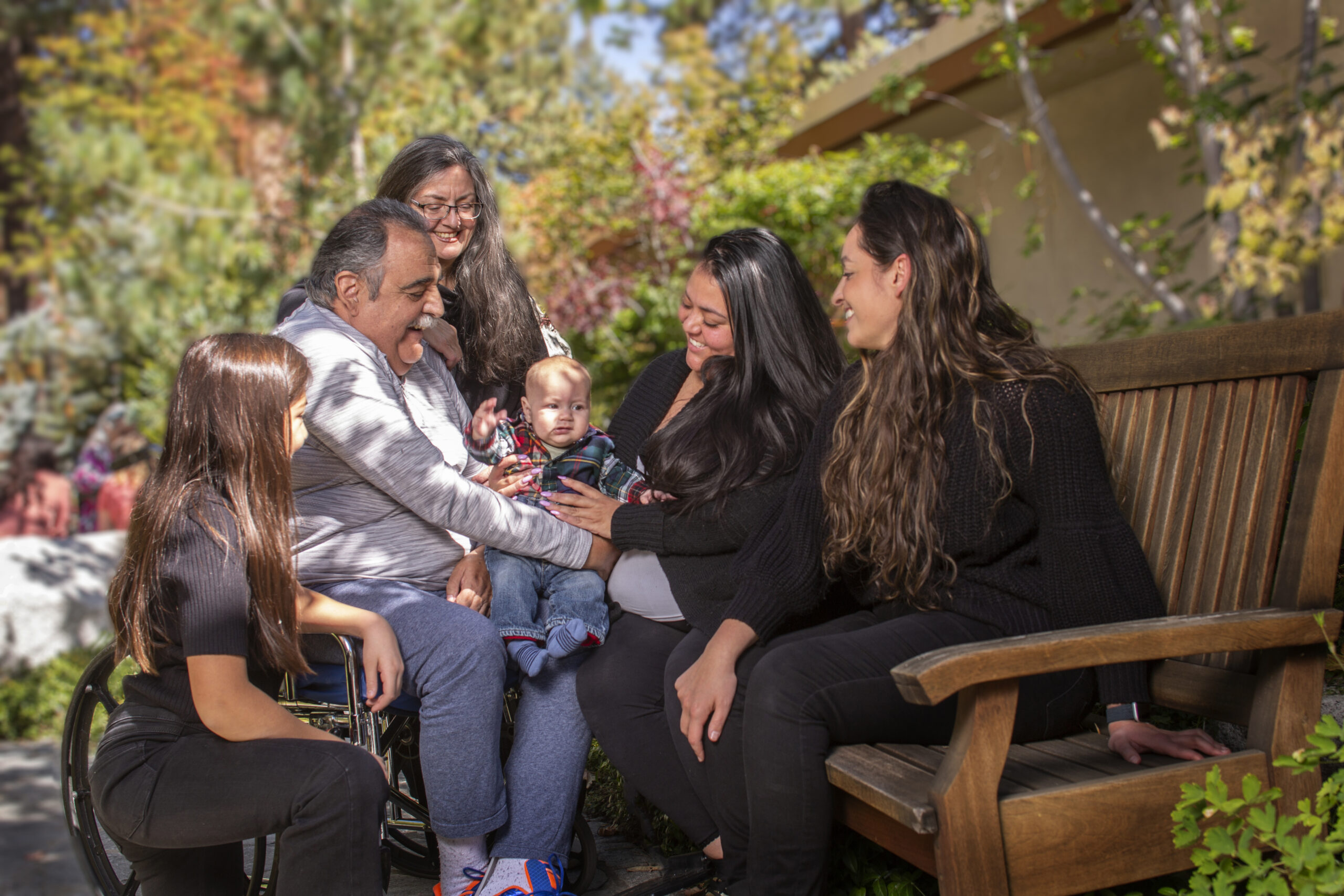 Family sitting and talking on a bench outside