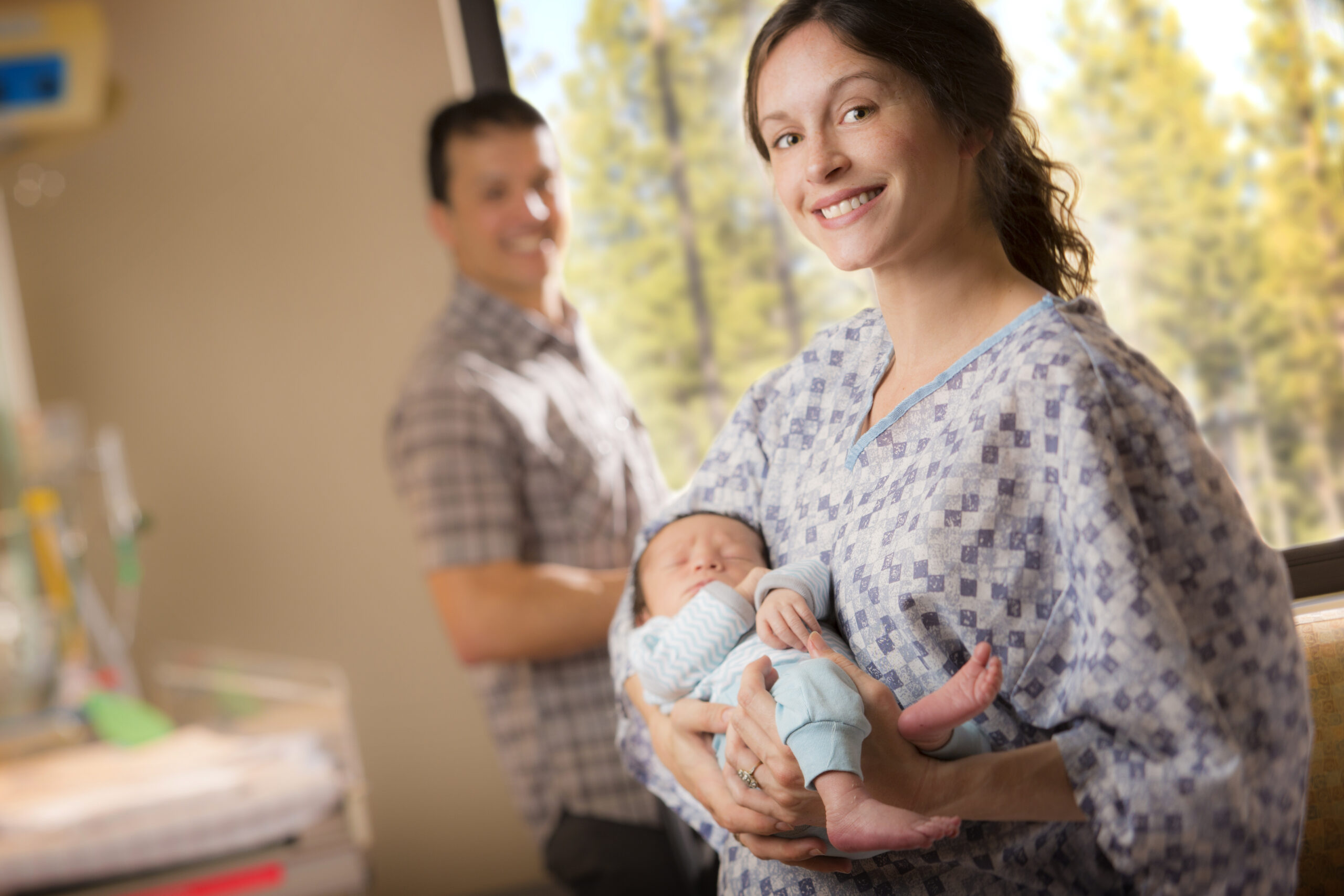 Woman holding her baby in a hospital gown and smiling.
