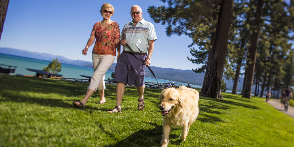 Older Couple walking next to a lake with a dog