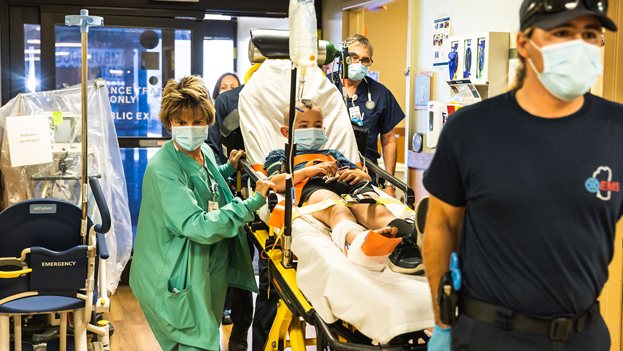 Pediatric patient arrives on a gurney with ankle bandaged.