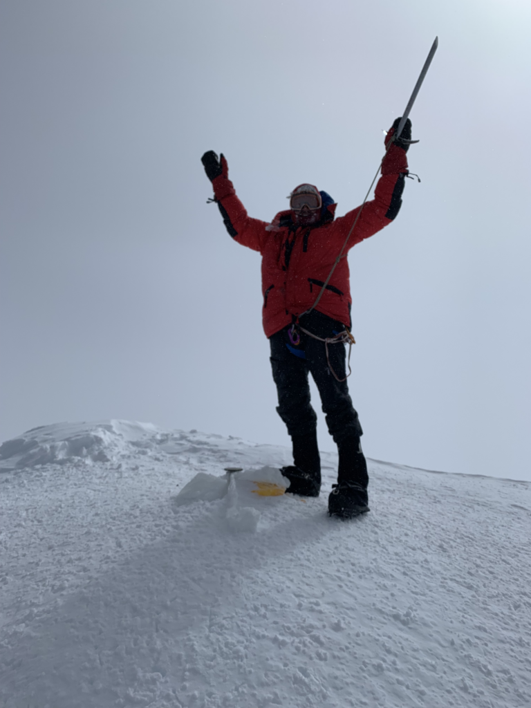 Dr. Habicht stands on top of a mountain peak.